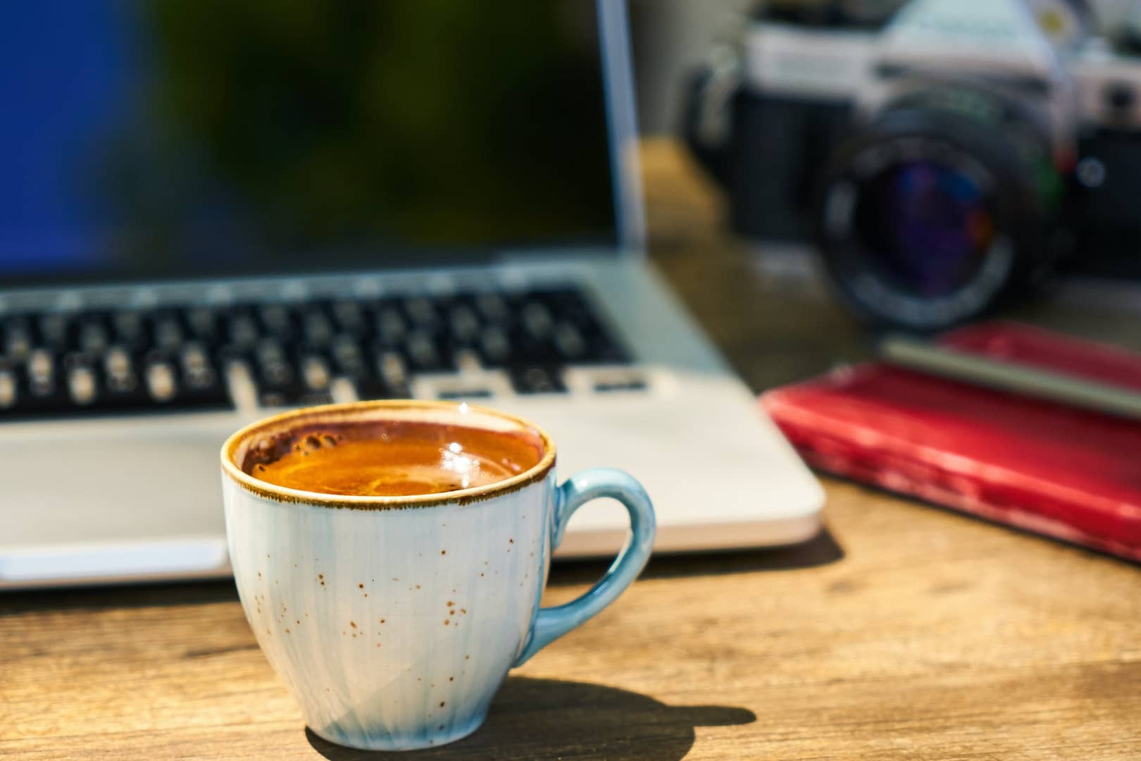 a cup of coffee and a camera on a wooden table in the workplace - virtual communities