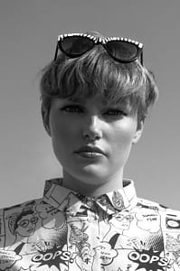 stylish model in modern sunglasses and shirt with comic ornament