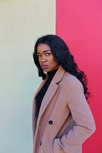 woman in brown blazer standing near white and red wall
