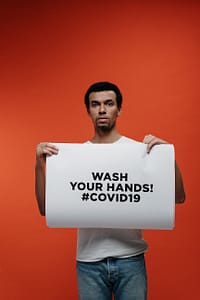 man holding a sign for guidance against coronavirus