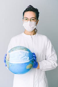 photo of person wearing protective wear while holding globe
