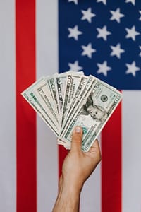 crop person demonstrating dollars against american flag
