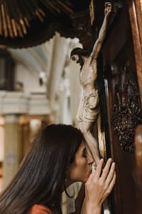 a woman kissing the sculpture of jesus christ