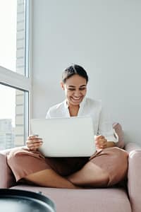 woman sitting on an armchair while working on a laptop