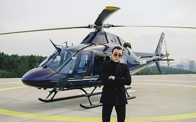 a man wearing a black outfit standing beside a helicopter