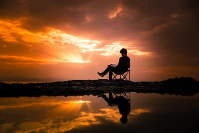 photo of man sitting on camping chair during dawn