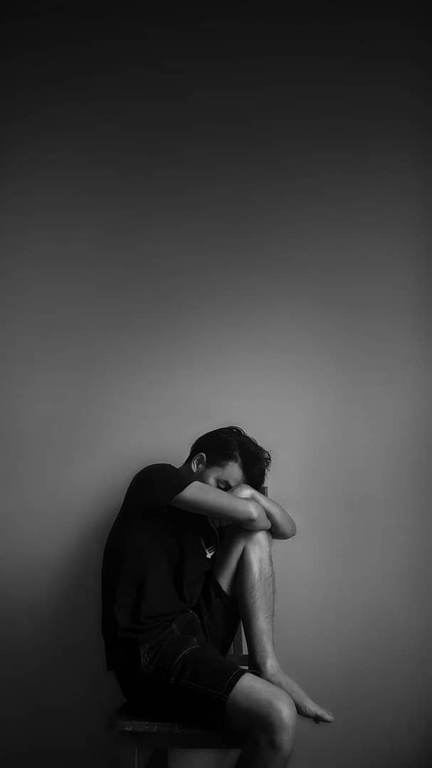Anxiety and depression influenced by the microbiome - grayscale photography of man sitting beside wall