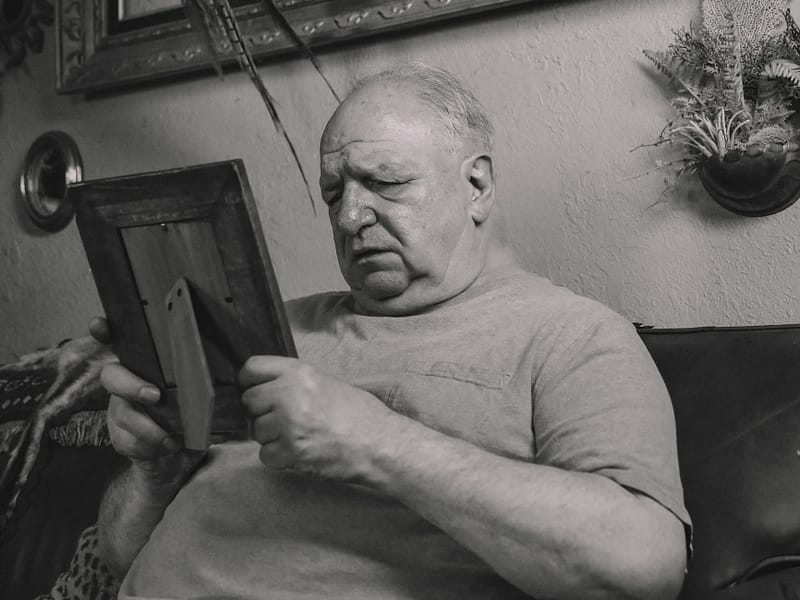 a grayscale photo of an elderly man holding a wooden frame - why appealing to white working class folk is a race to the bottom/
