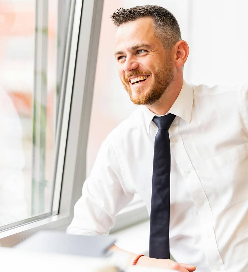 smiling man wearing a shirt and tie - Careerism: Self-interest's acceptable face